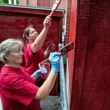 Volunteers painting a building red